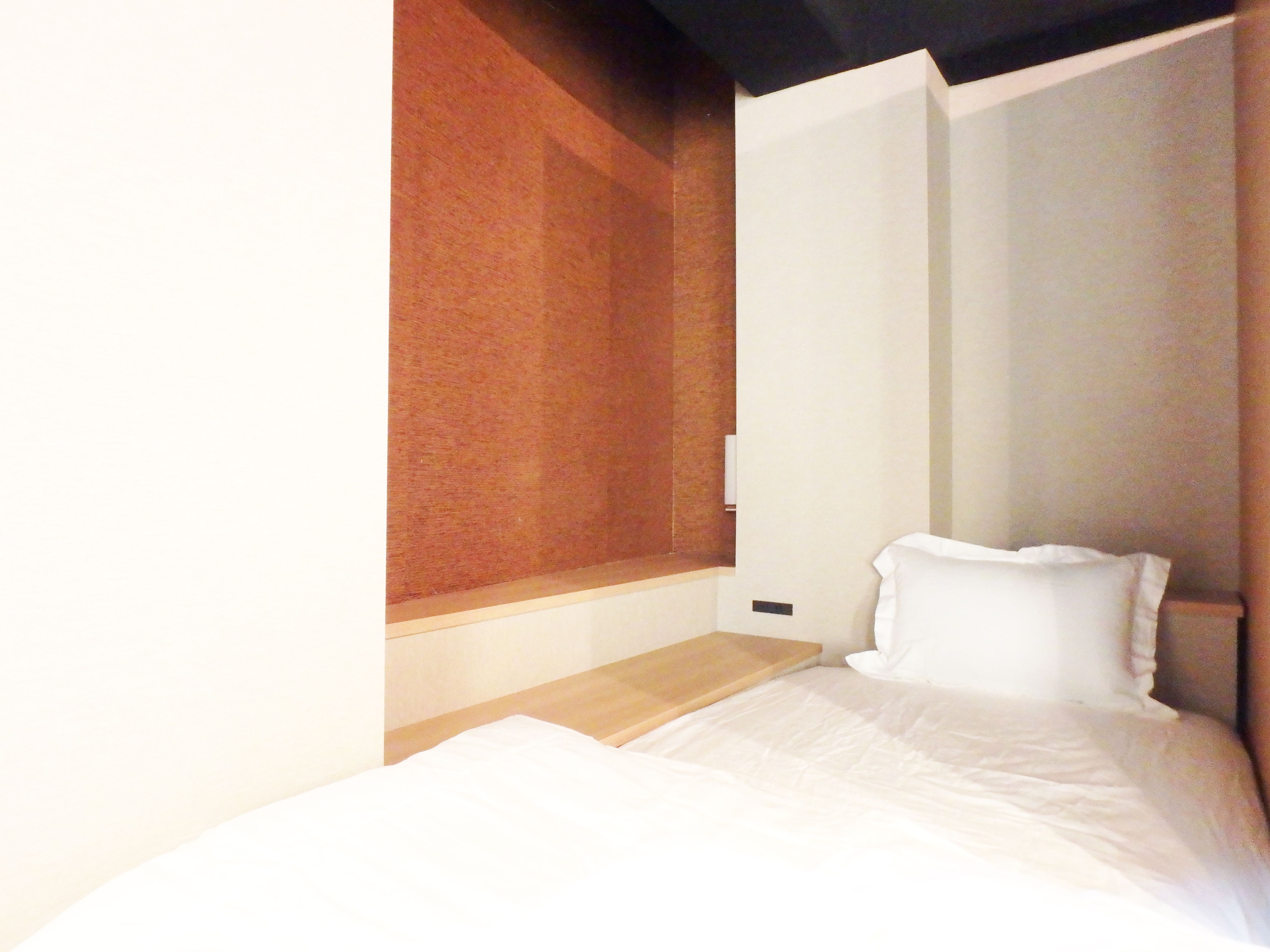 Single bed in cozy alcove with terracotta textured wall