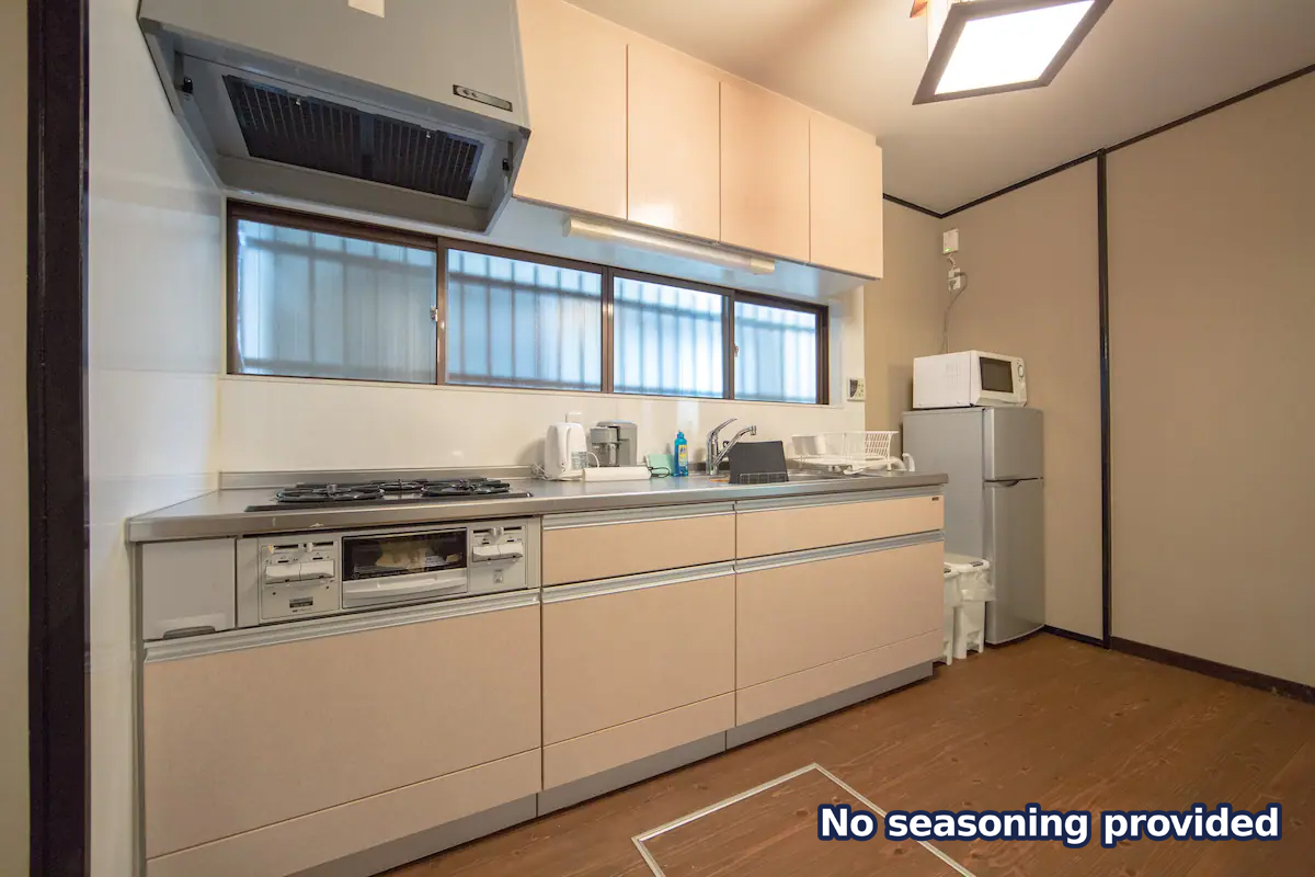Full kitchen with gas stove, range hood, stainless steel counters, and refrigerator with microwave